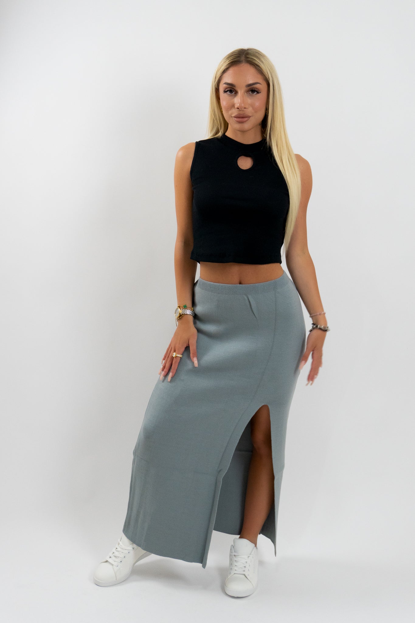 Η Rosethia γκρι μάξι φούστα με σκίσιμο και μοντέρνο σχεδιασμό, σε casual συνδυασμό με μαύρο crop top και λευκά sneakers — τέλεια για κάθε καθημερινή περίσταση.