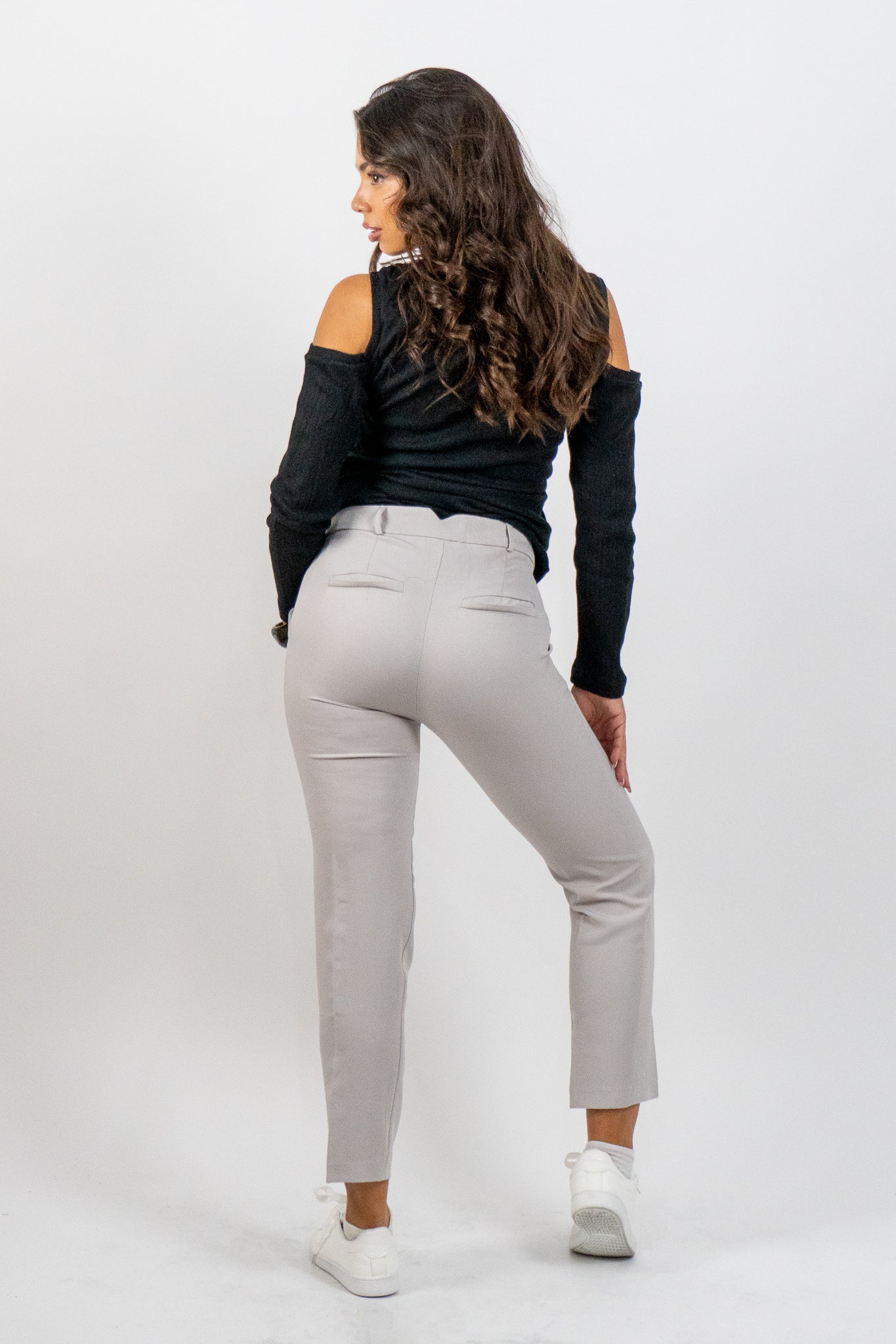 Woman wearing a black top and gray pants on a white background