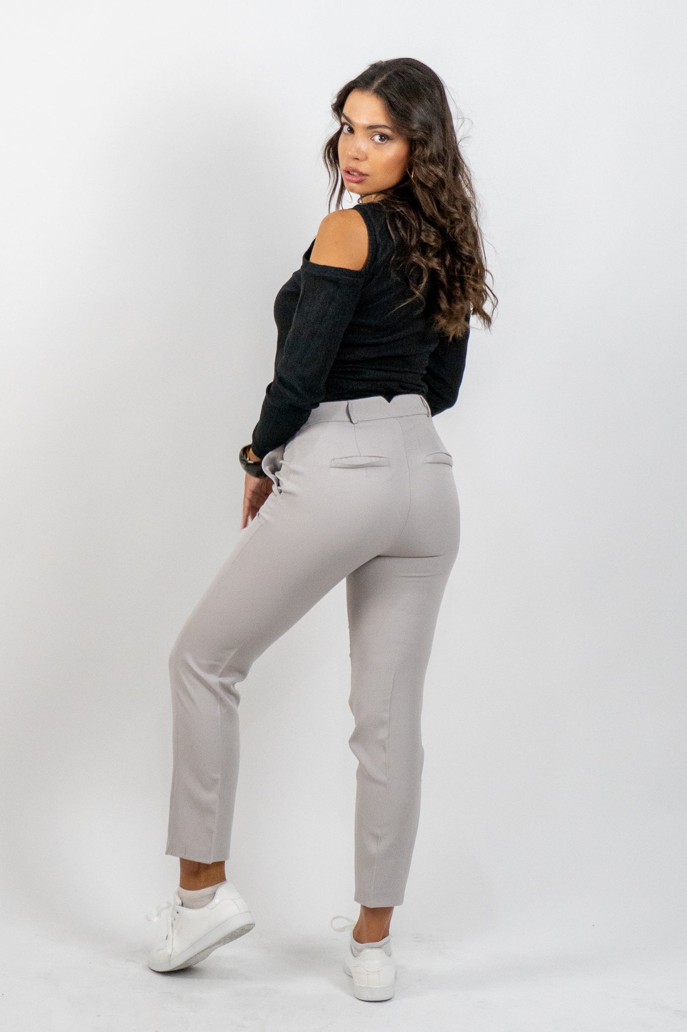 Woman wearing a black top and gray pants on a white background