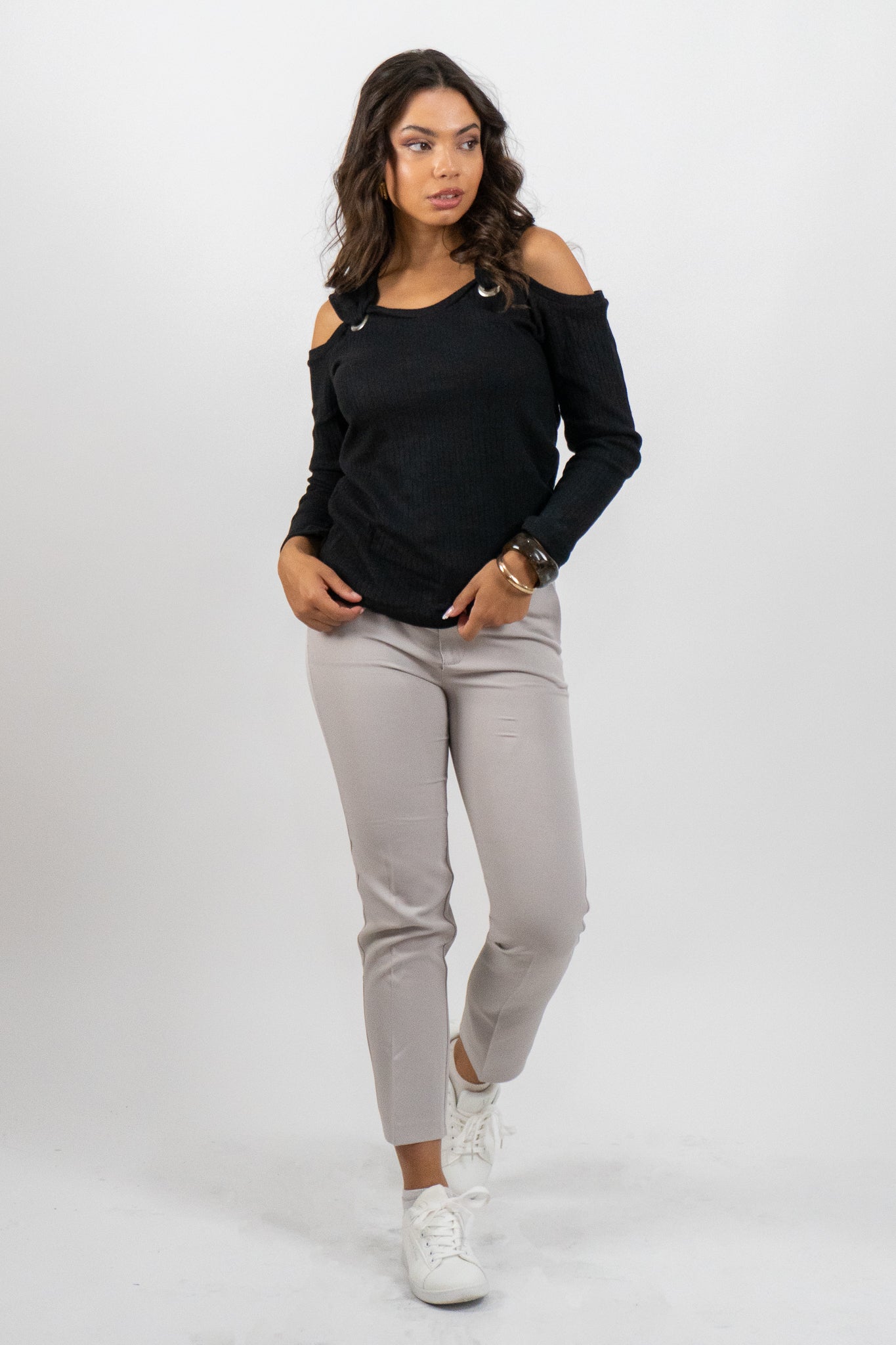 Woman wearing a black long-sleeve top and gray pants on a white background