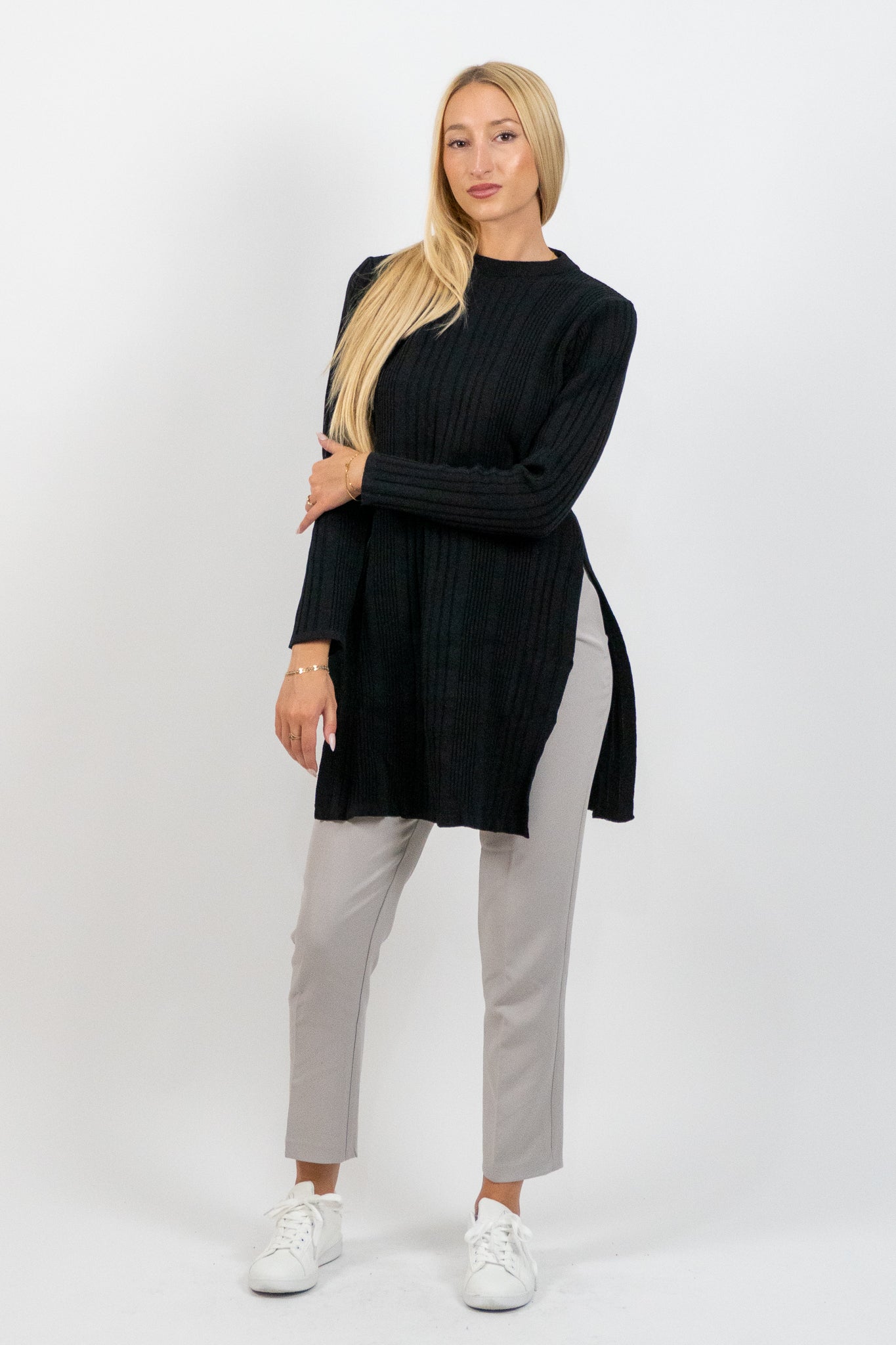 Woman wearing a black sweater and gray pants on a white background