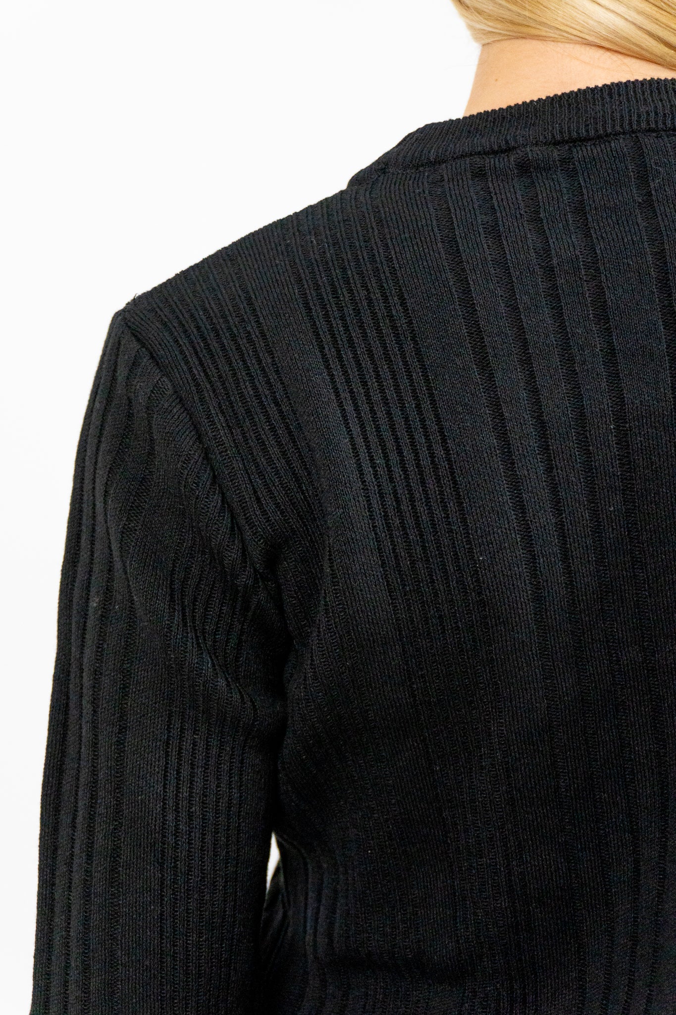 Close-up of a black ribbed sweater on a white background