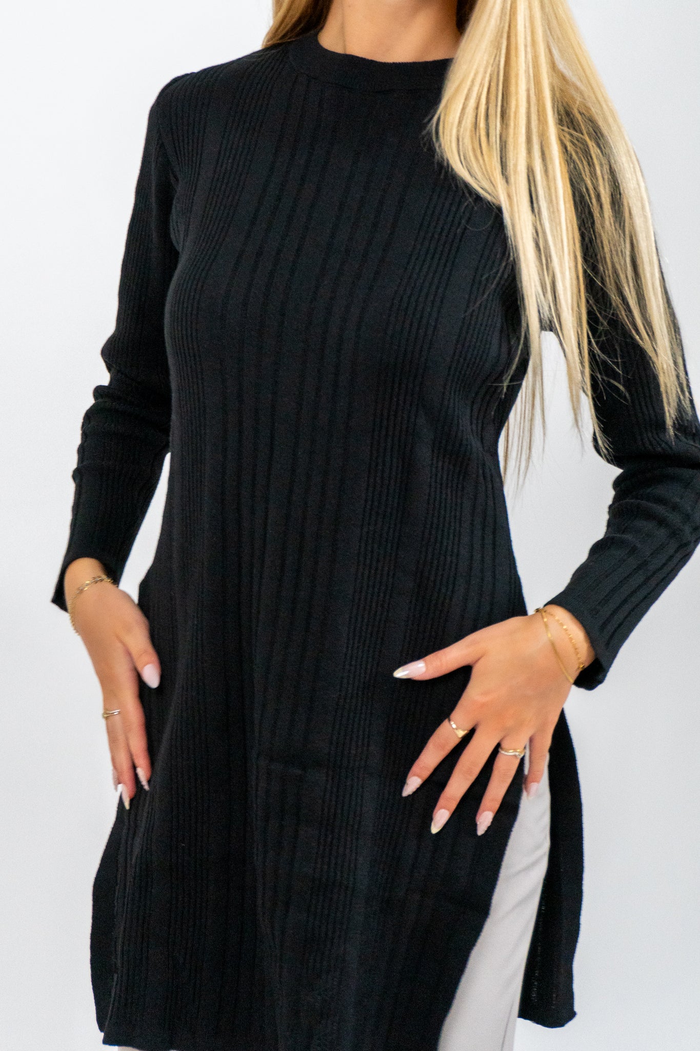 Black ribbed sweater dress worn by a person on a white background