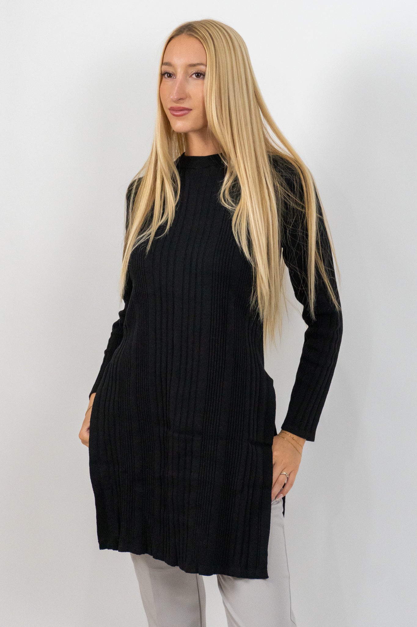 Woman wearing a black long-sleeve dress against a white background