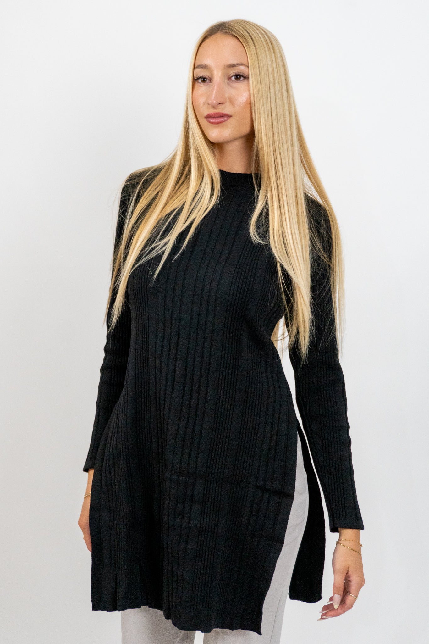 Woman wearing a black ribbed dress against a white background