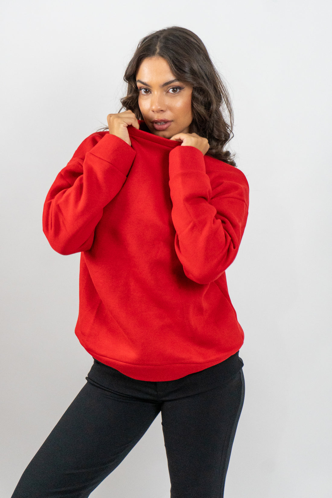 Woman wearing a red sweater and black pants on a white background