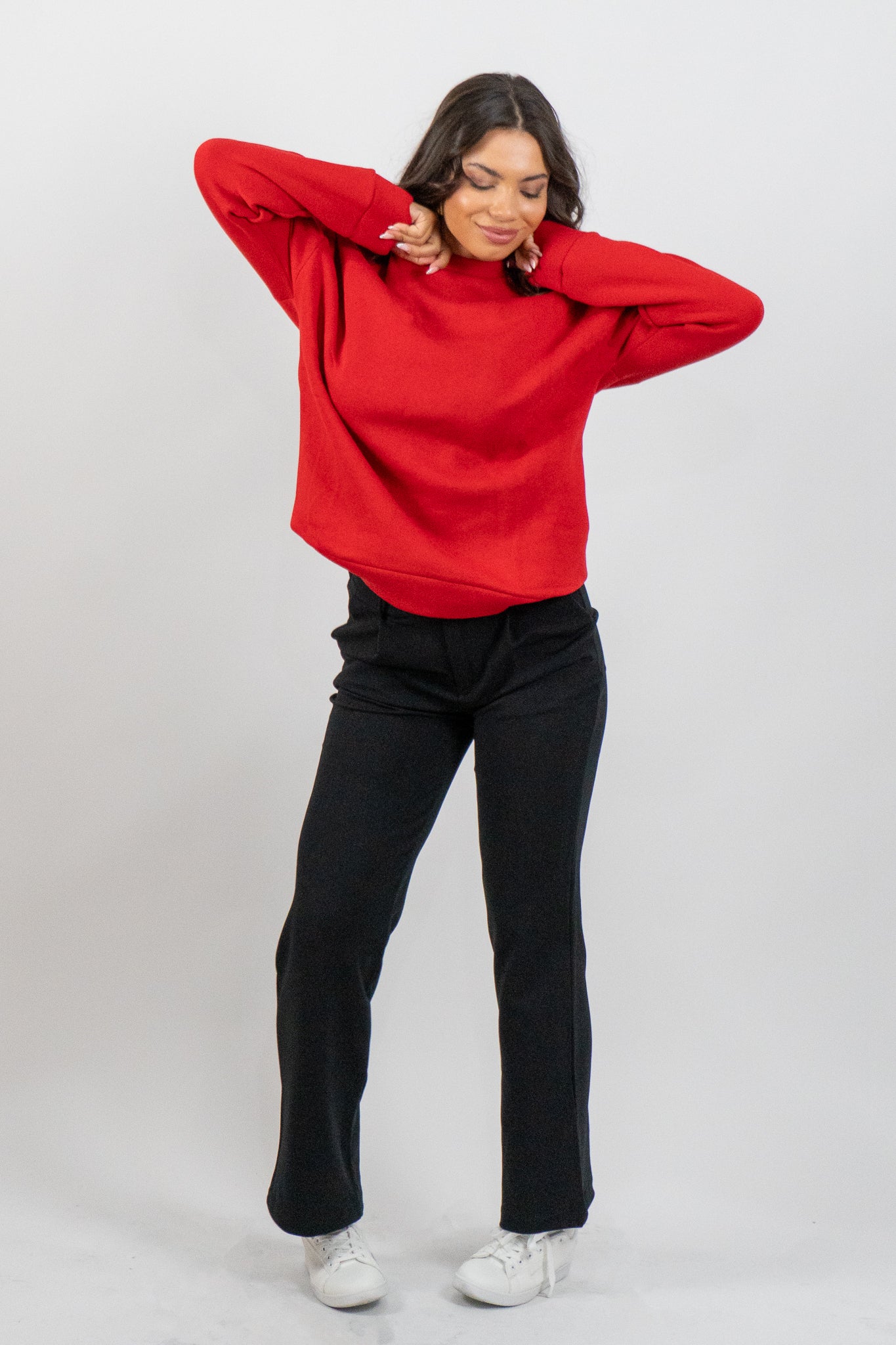 Woman wearing a red sweatshirt and black pants on a white background