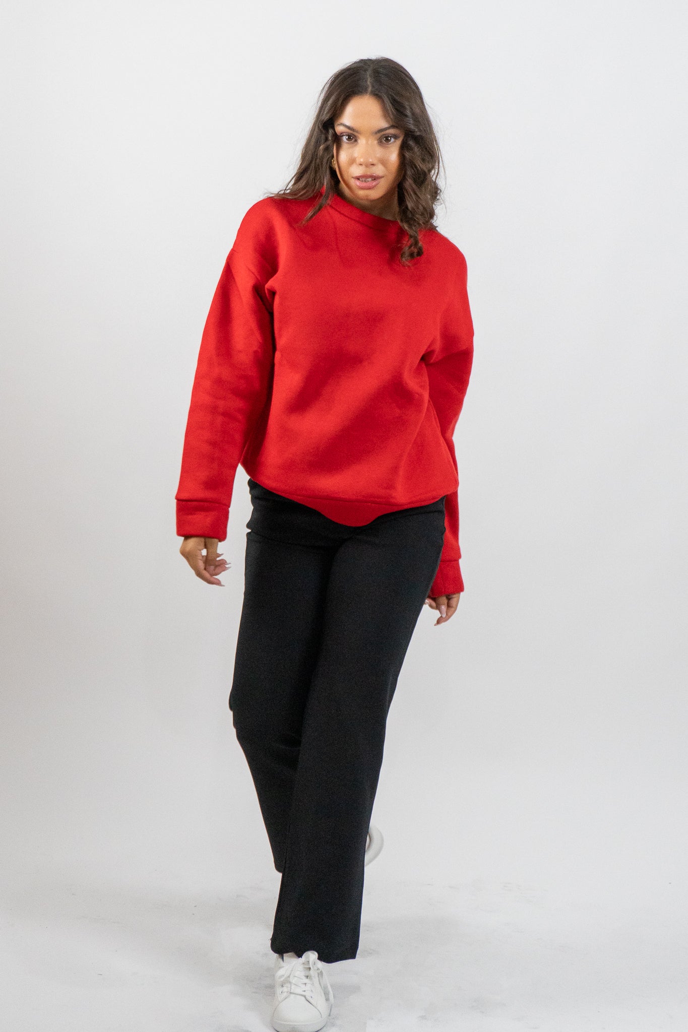 Woman wearing a red sweater and black pants on a white background
