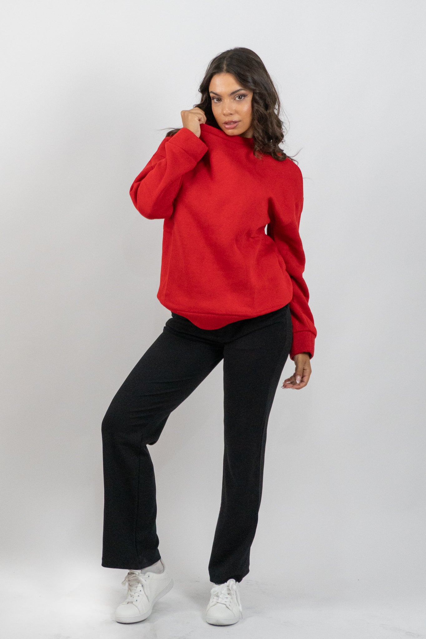 Woman wearing a red hoodie and black pants on a white background